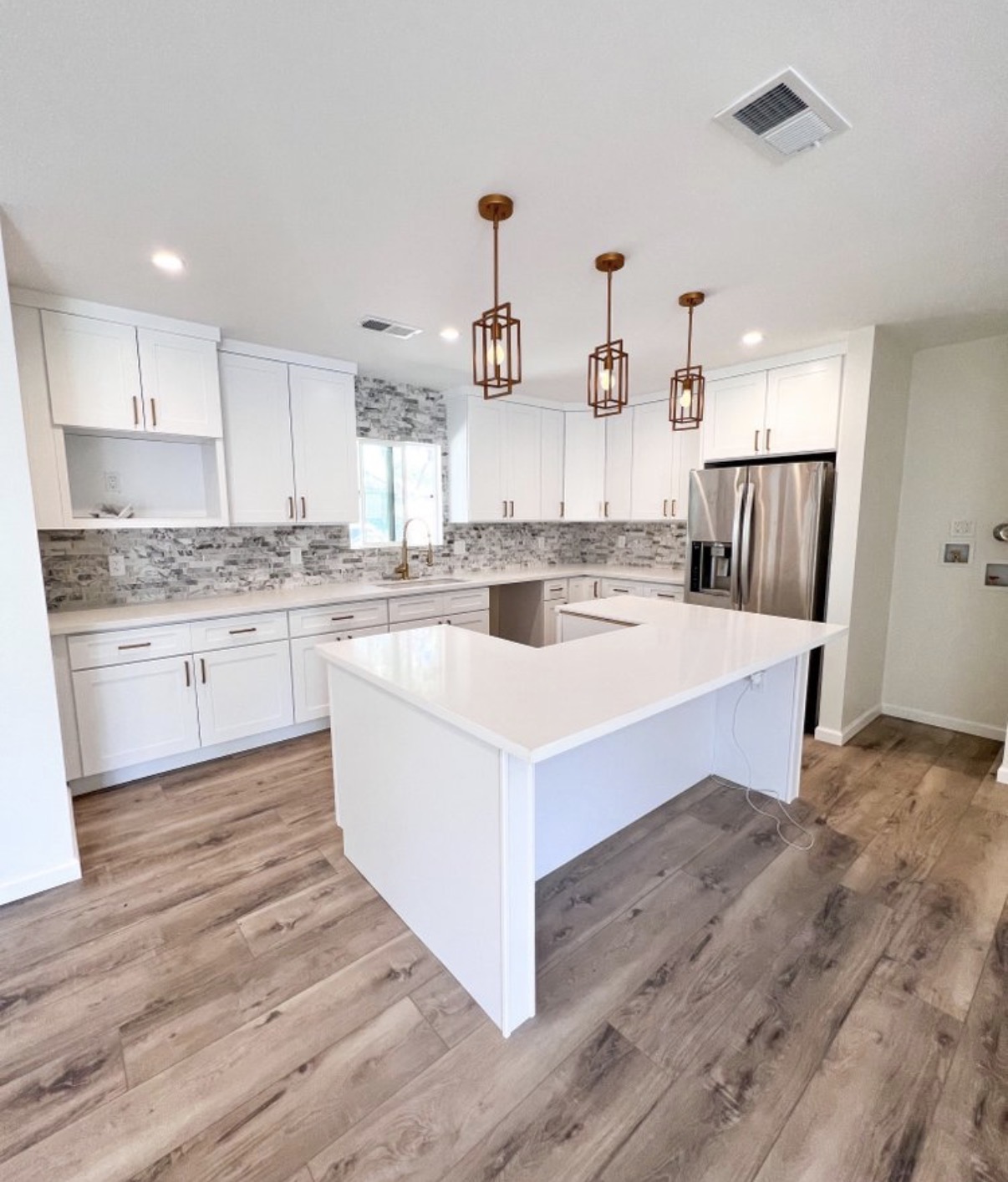 Open white kitchen with quartz island & pendant lights