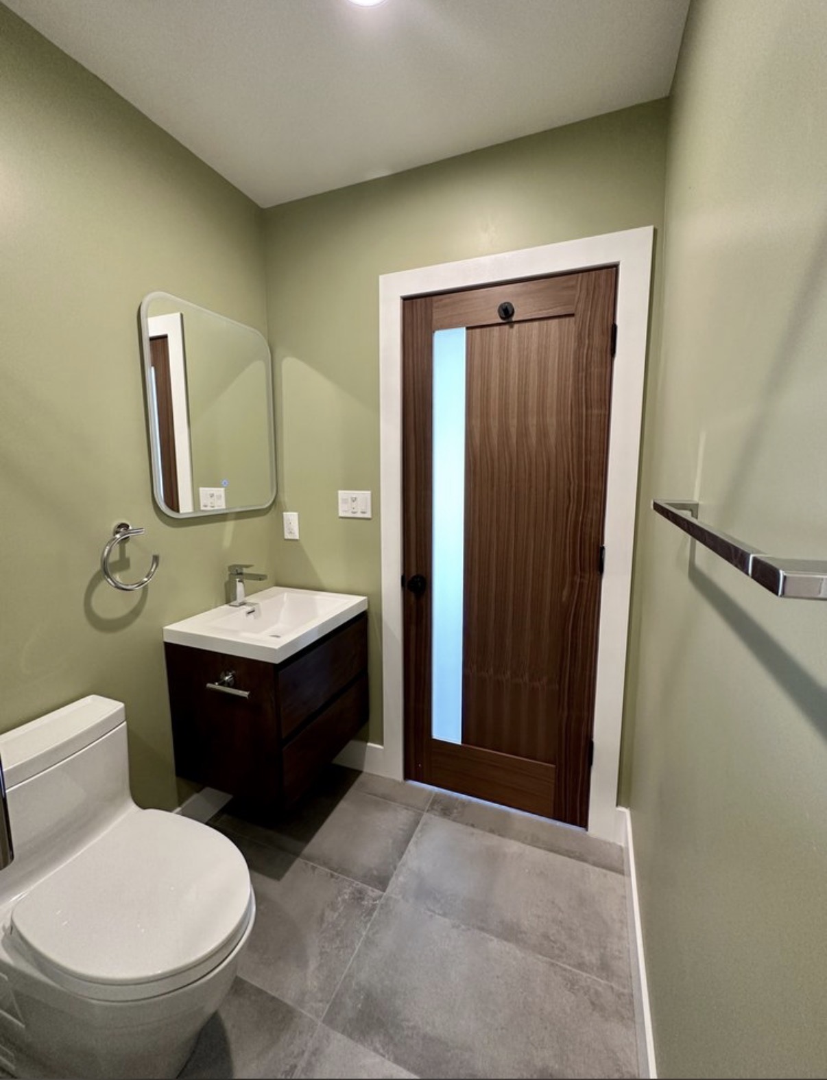 Sage green powder room with walnut door
